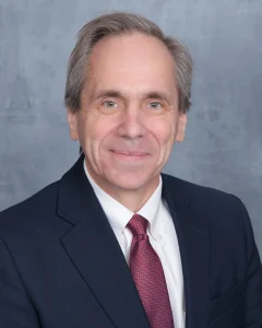 A head-and-shoulders photo of Dean Patrick Vivier wearing a suit and tie